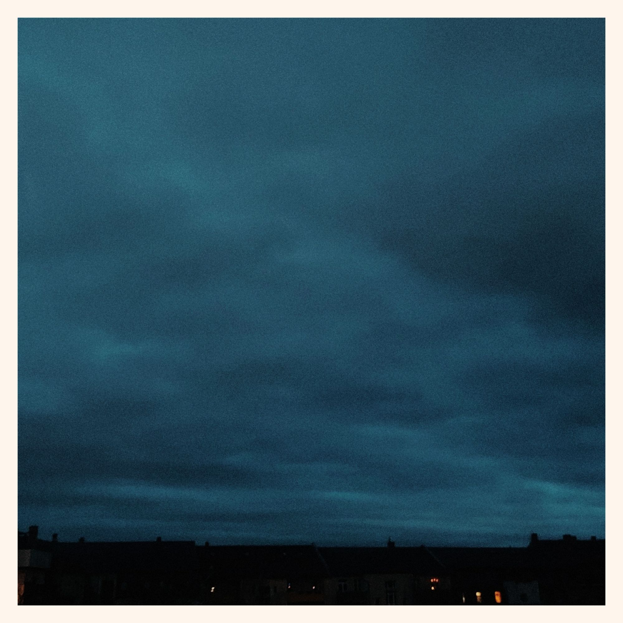 Dark sky, clouds above city roofs.