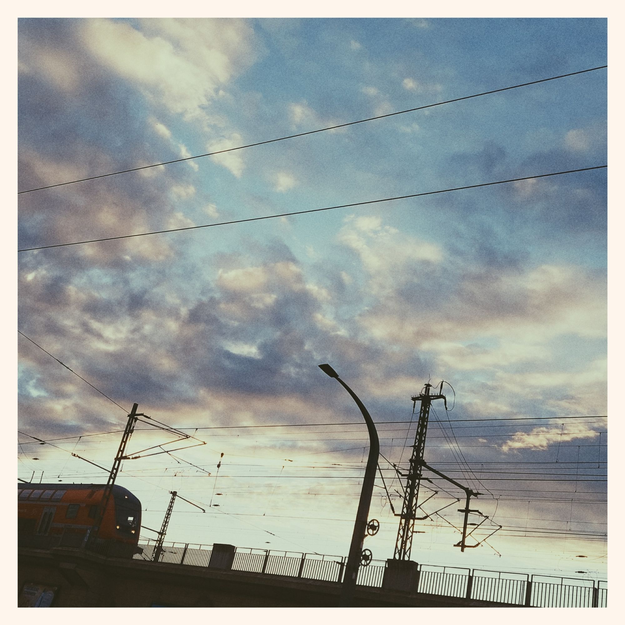 Clouds in a coloured sky. Railway infrastructure below.