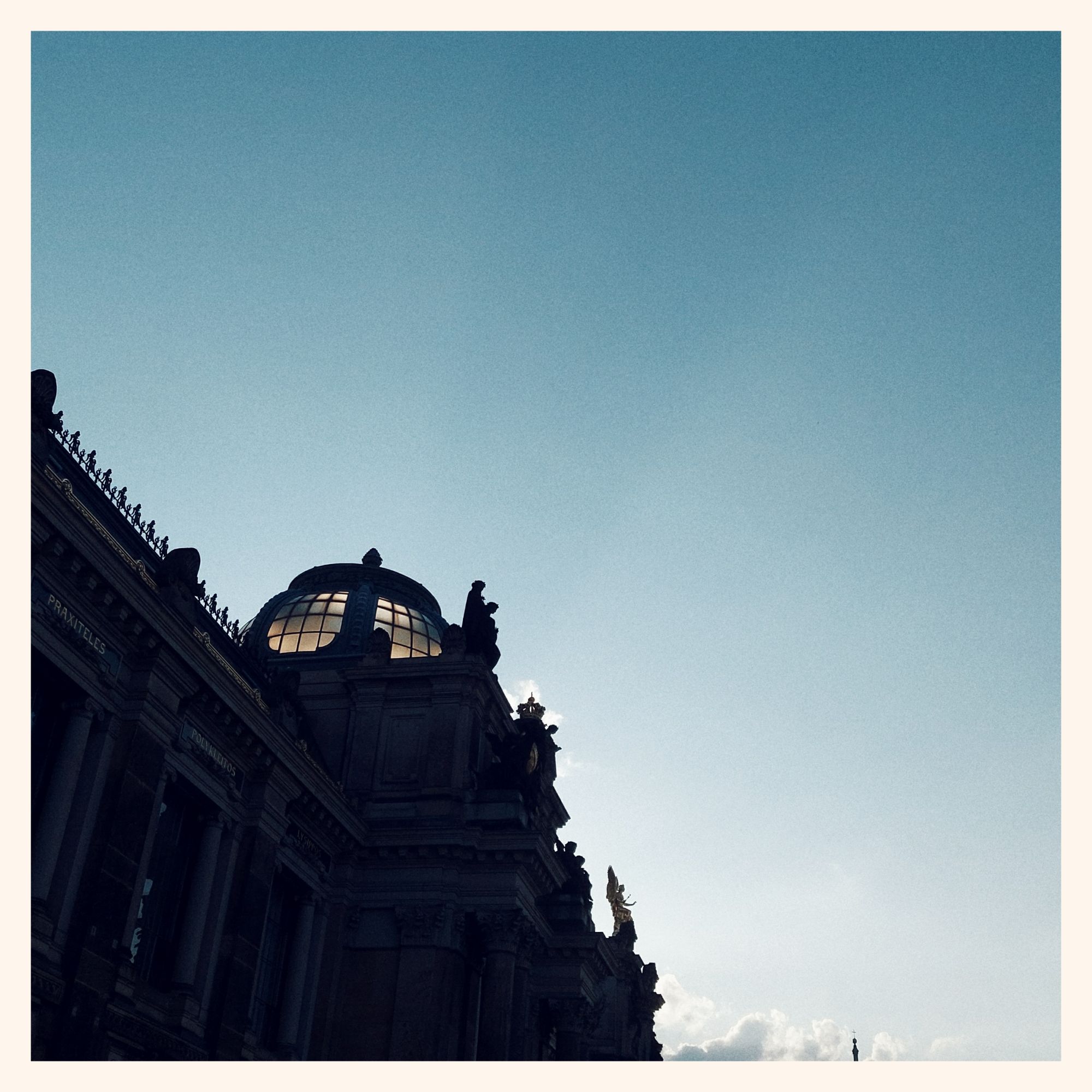 Quiet sky, sunset behind the glass dome topping an old building. 