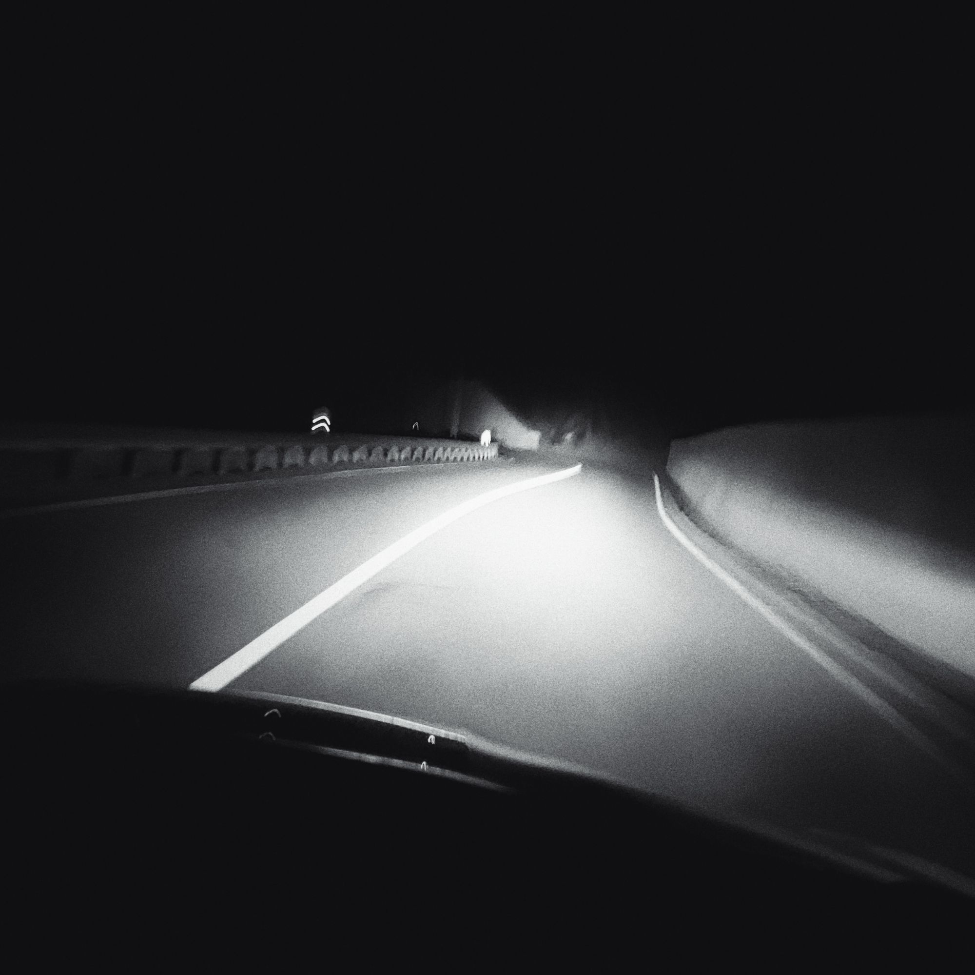 A street in headlights. Blurred, monochrome, night.