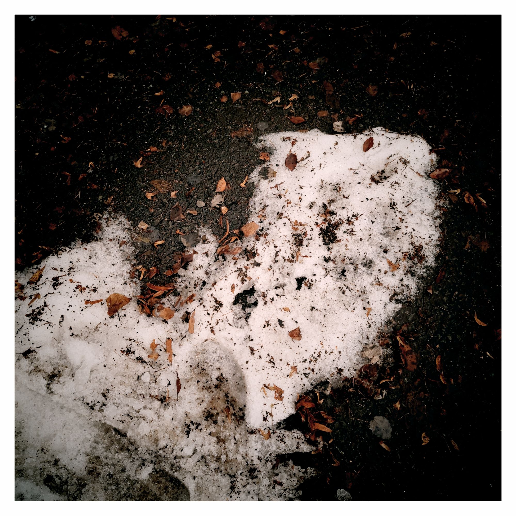A small heap of dirty snow on a parking lot.