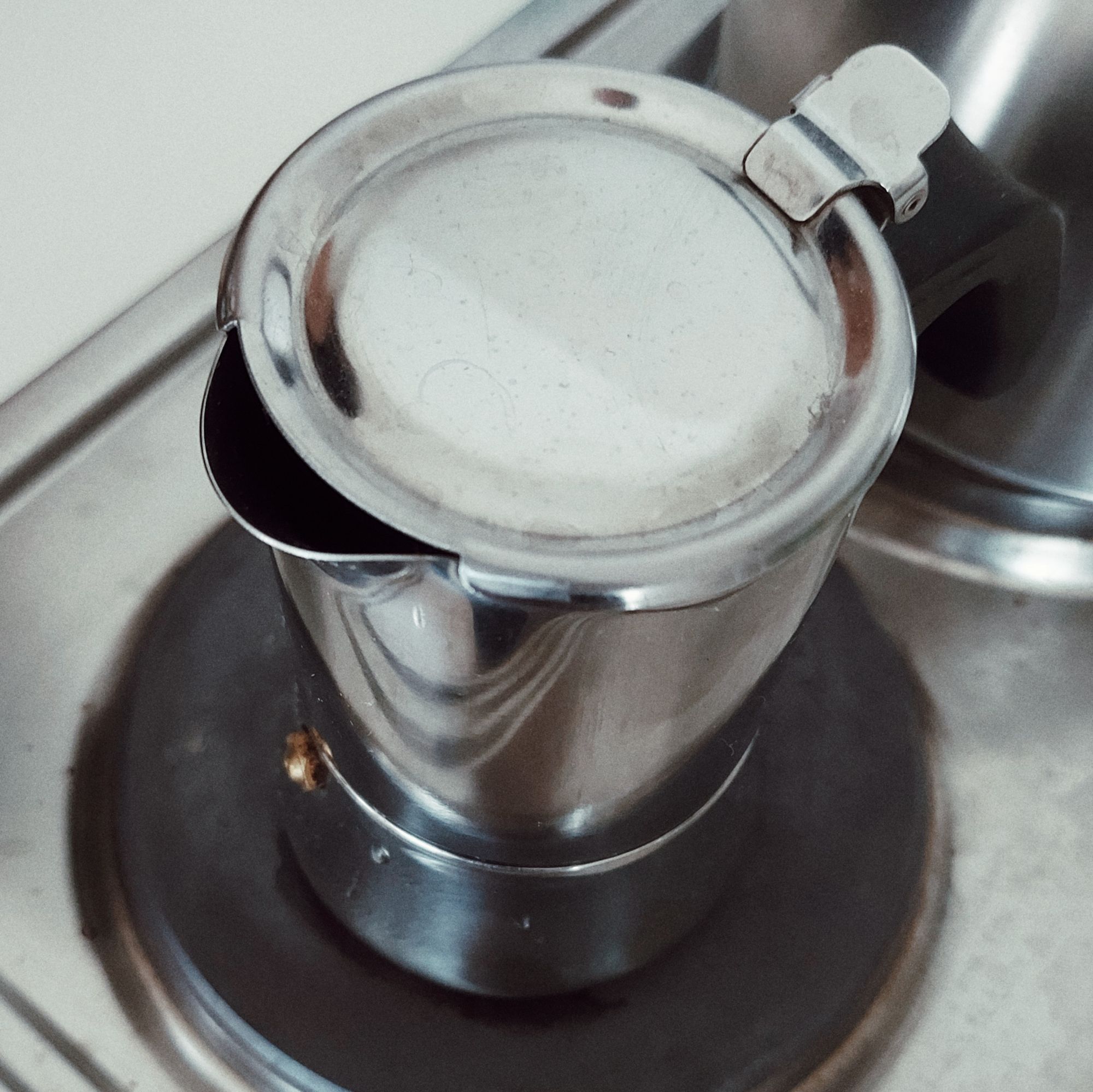 A small espresso maker on an old oven. 