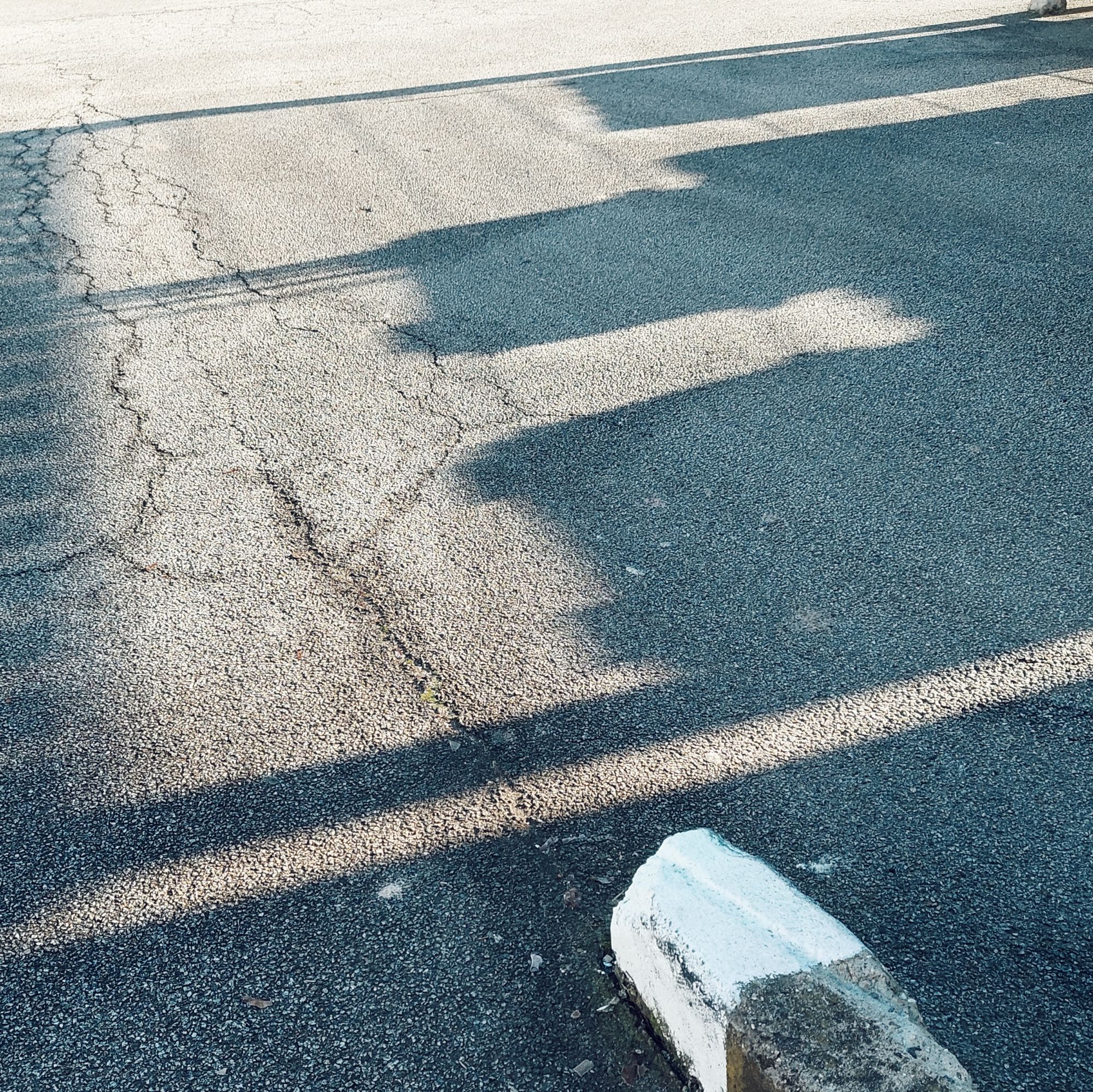 Shadows and sun on the concrete surface of a parking lot.