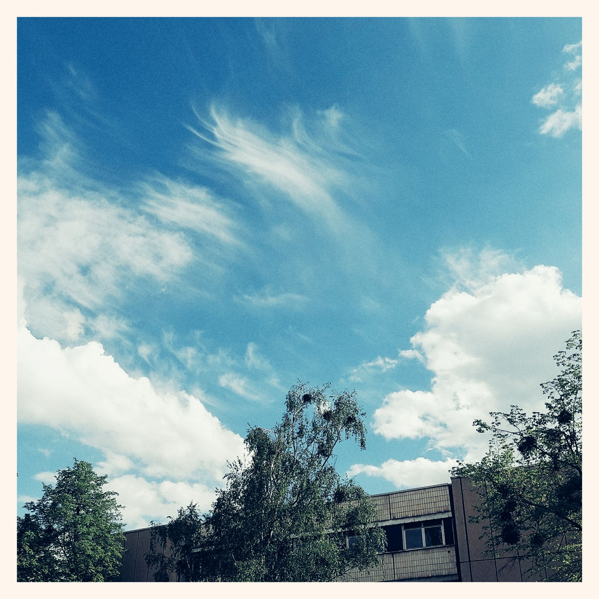 Blue sky, thin clouds above a socialist modern building.