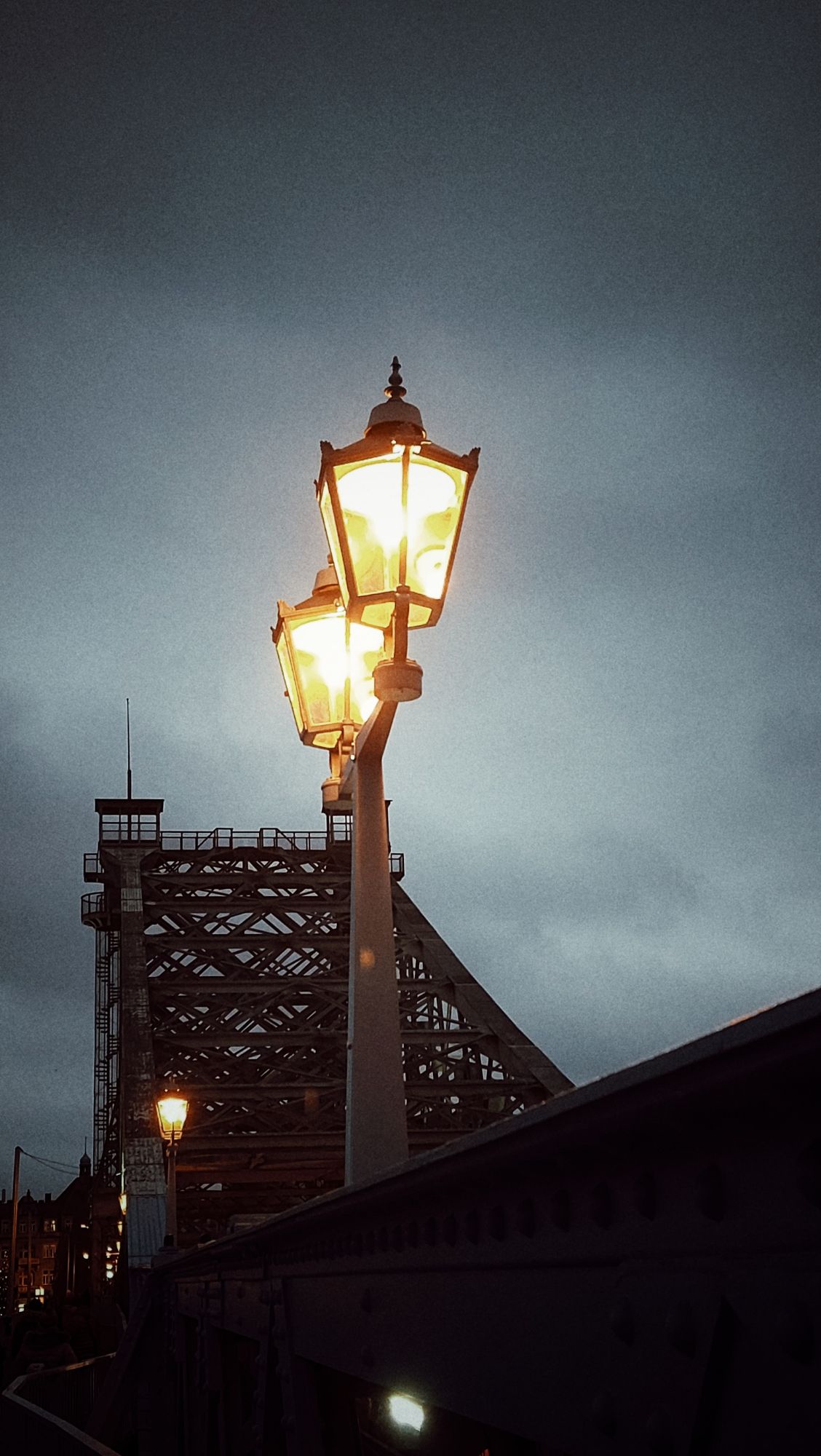 Lanterns on an old bridge, greyish sky behind.