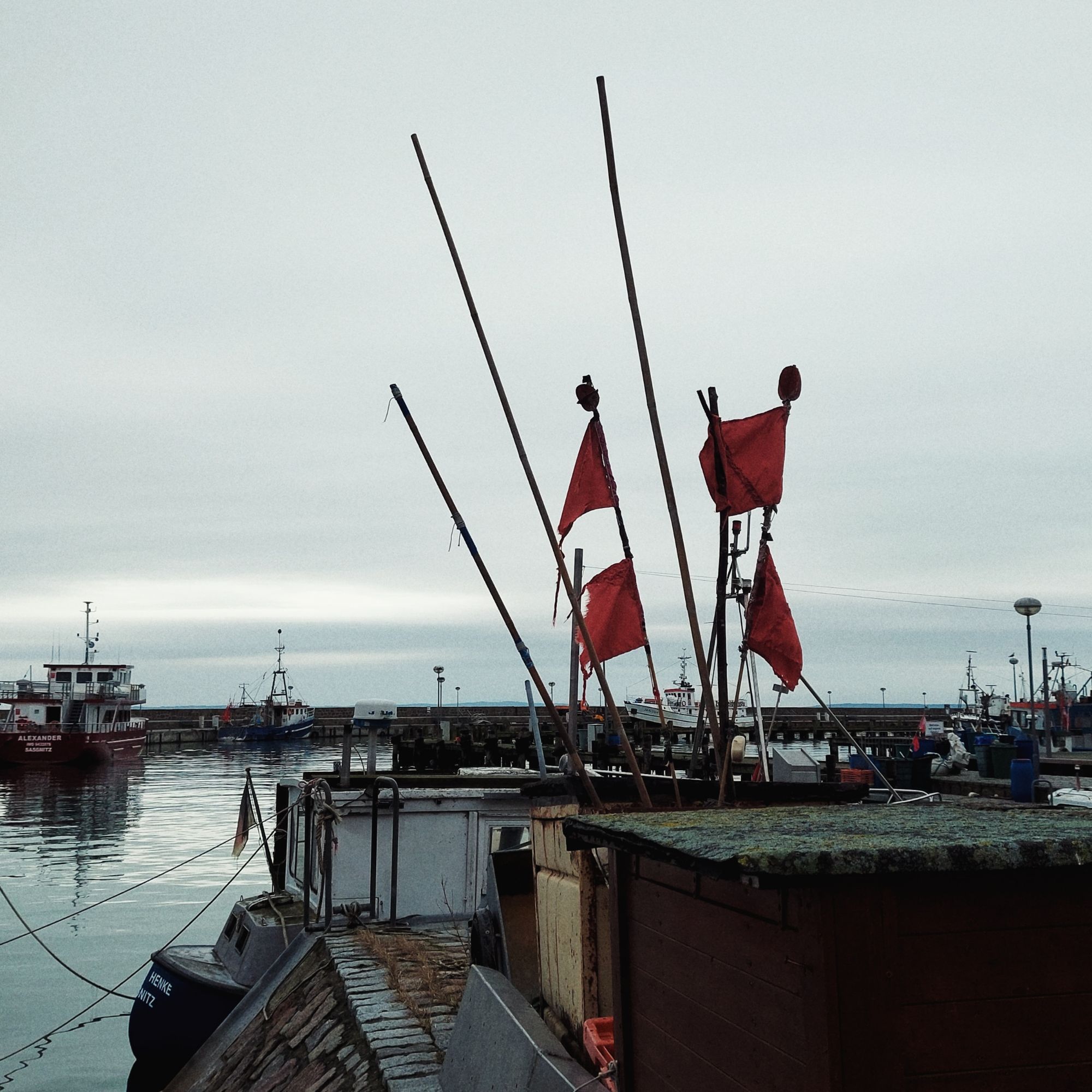 Red flags kept in an old equipment box, in front of the harbour and the sea.