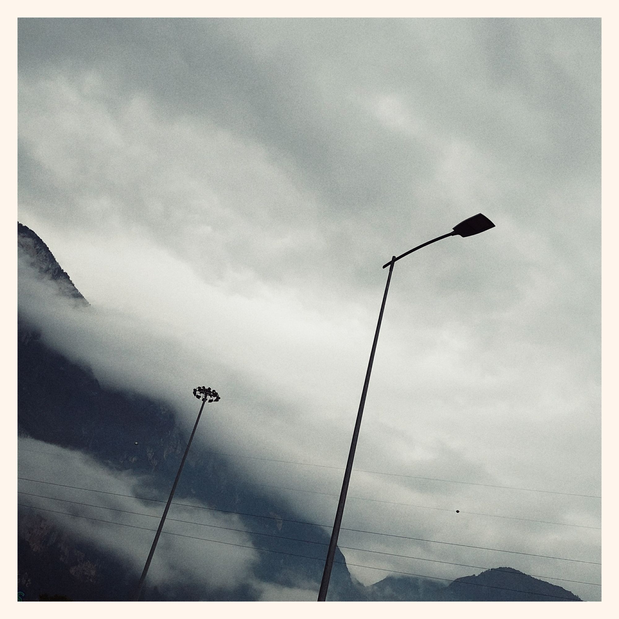 Grey clouds over dark mountains. Lanterns in front 