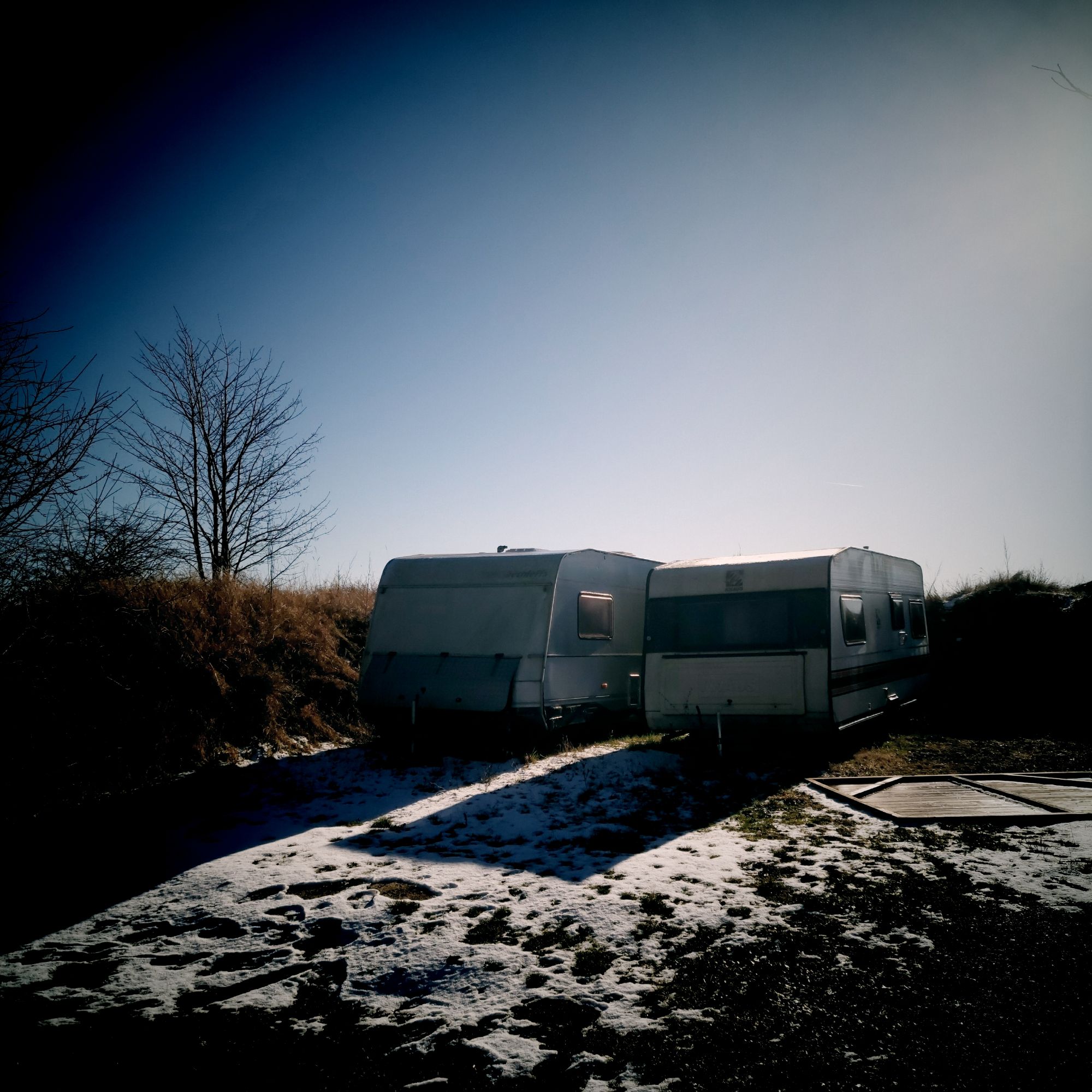 Two abandoned trailers parked under a blue sky.