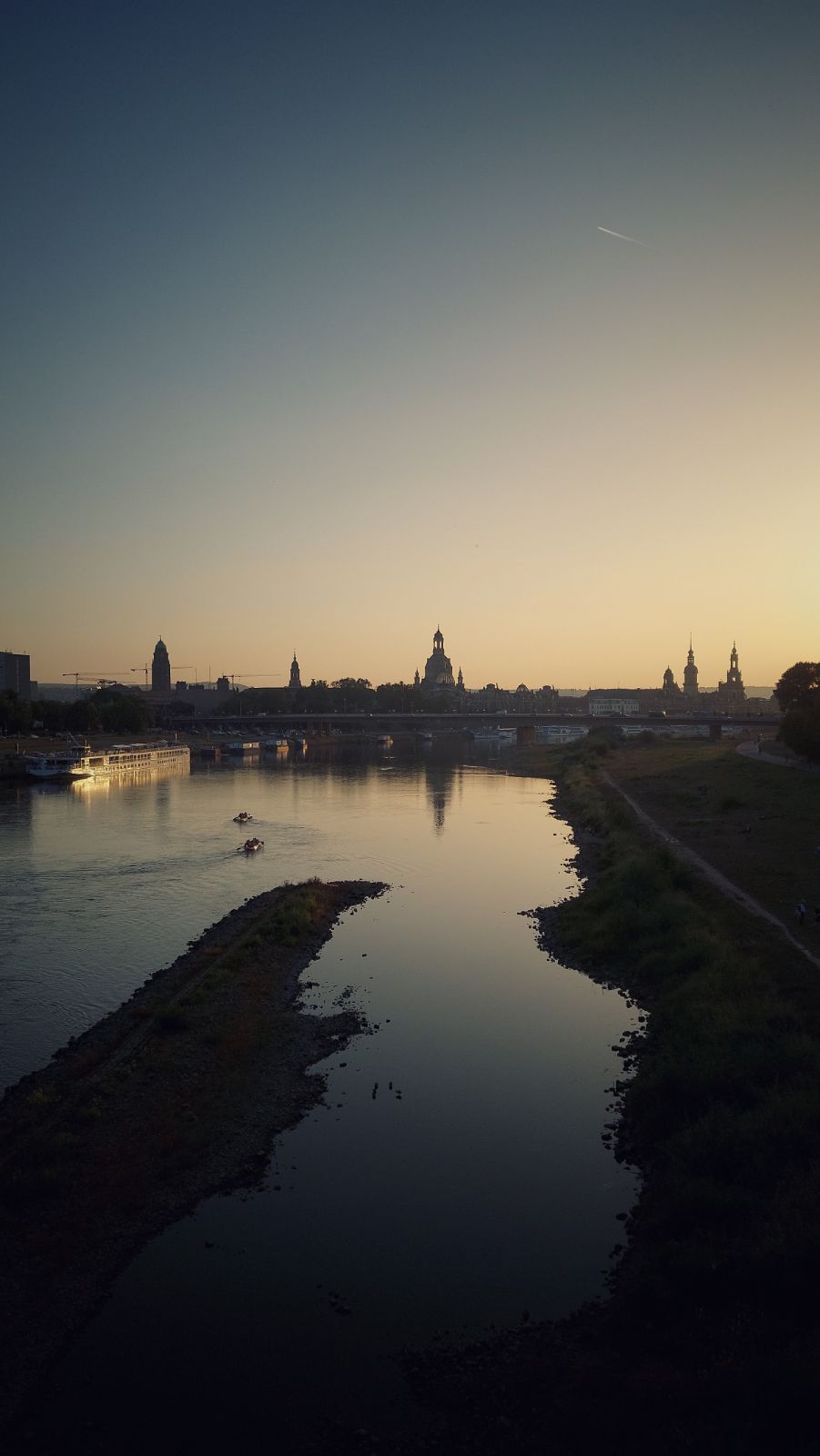 Old Dresden baroque skyline in early dusk. River banks in front of the picture. Quiet waters.