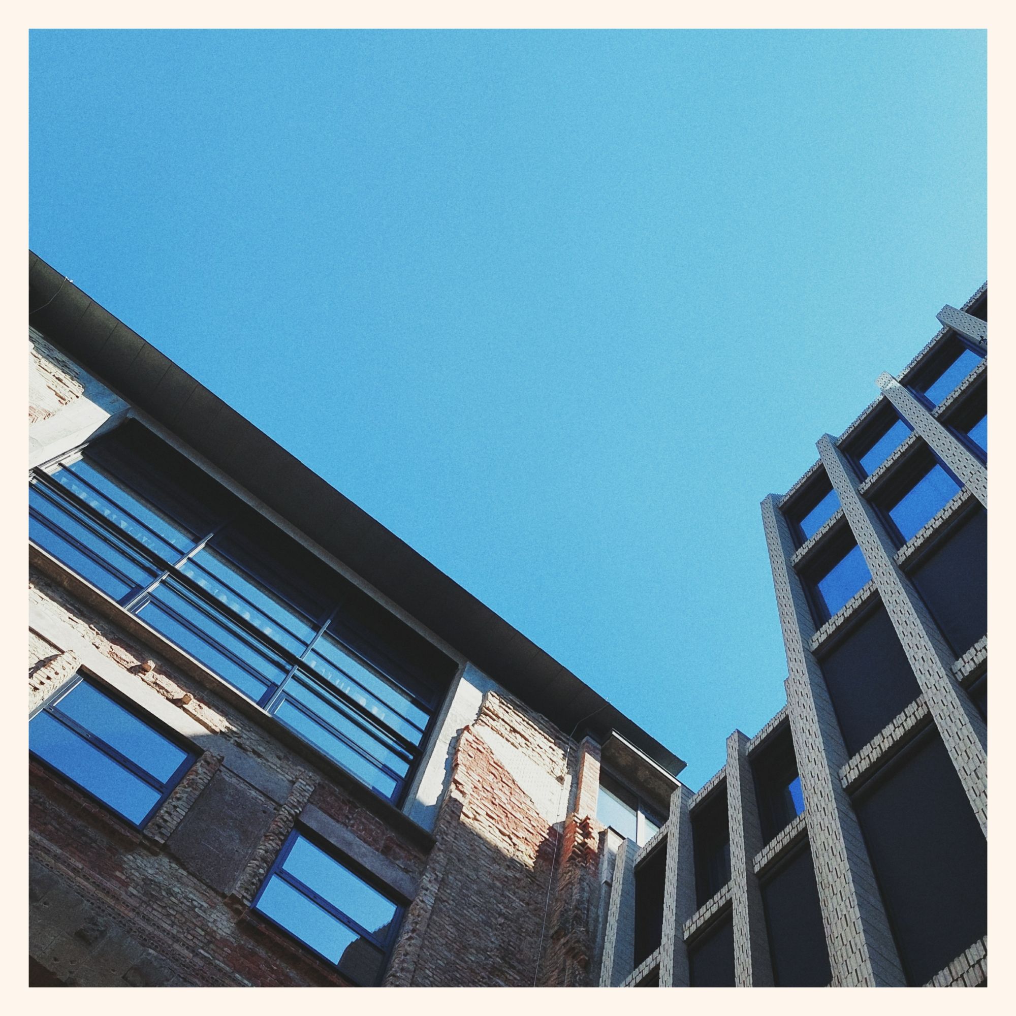 Blue cloudless sky. Old Tacheles house facade dominated by new urban architecture.