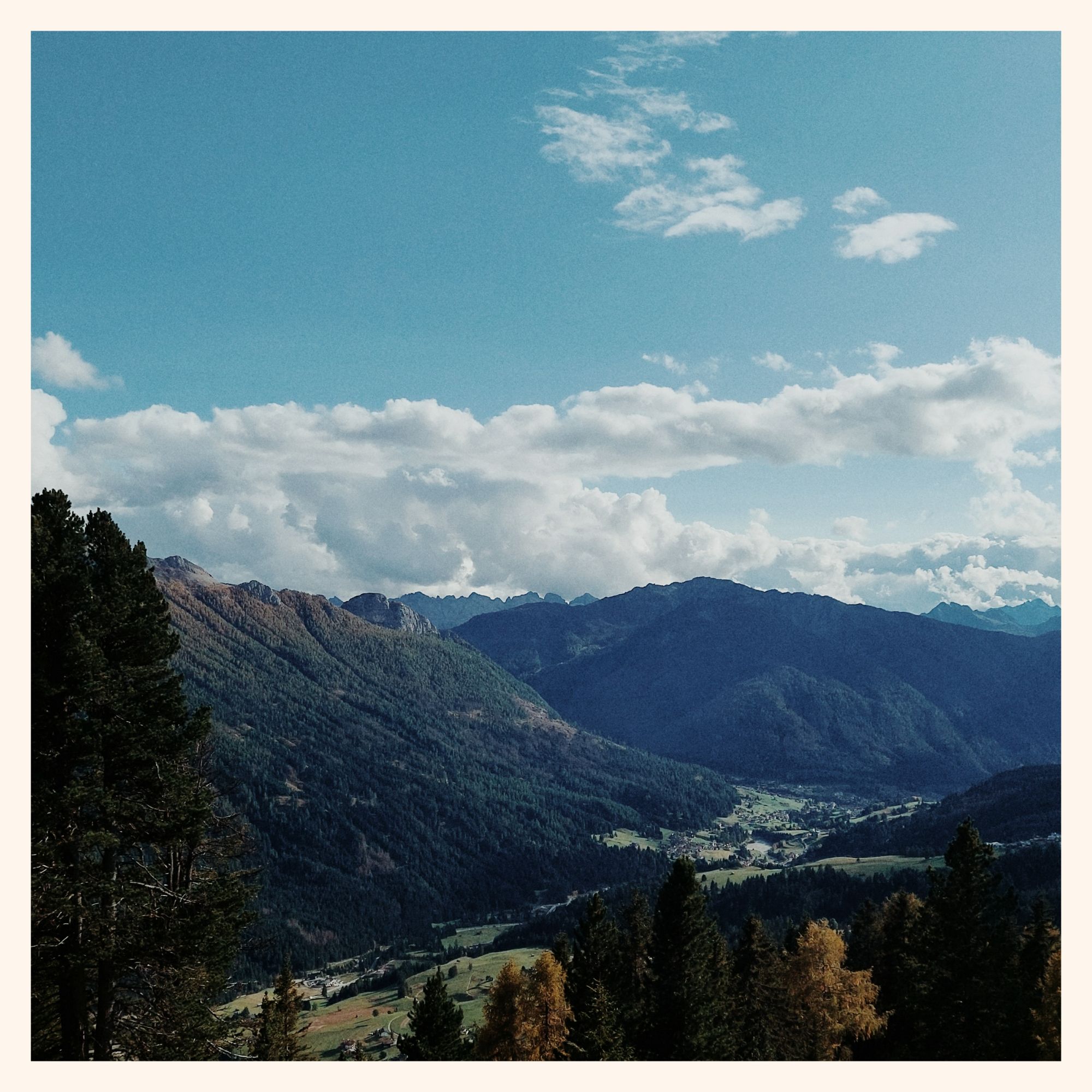 Panoramic view from a mountain. Clouds on blue sky, a valley below.