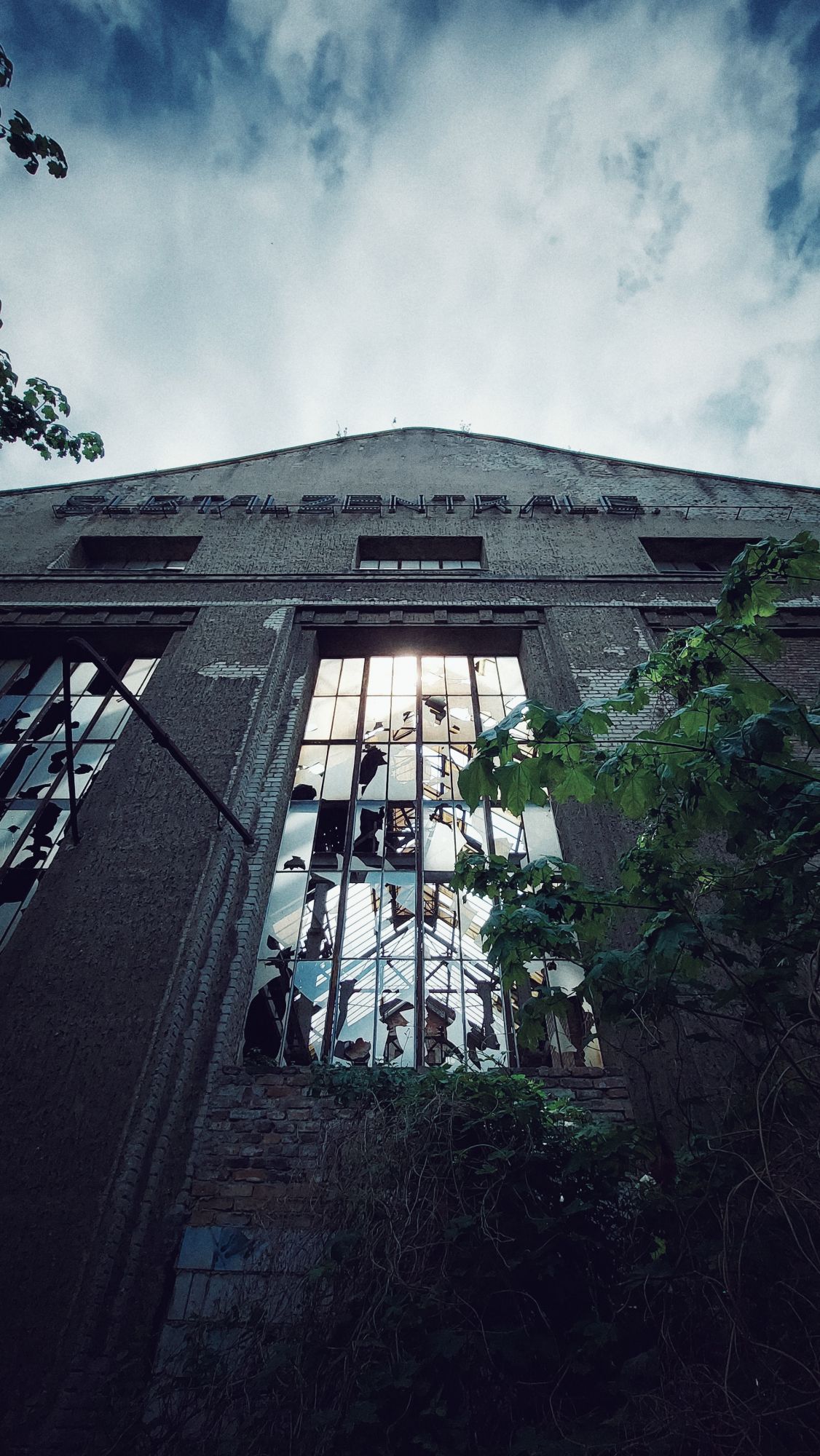 An abandoned building. Facade seen by looking up. Sun through windows, and letters reading ELBTALZENTRALE.