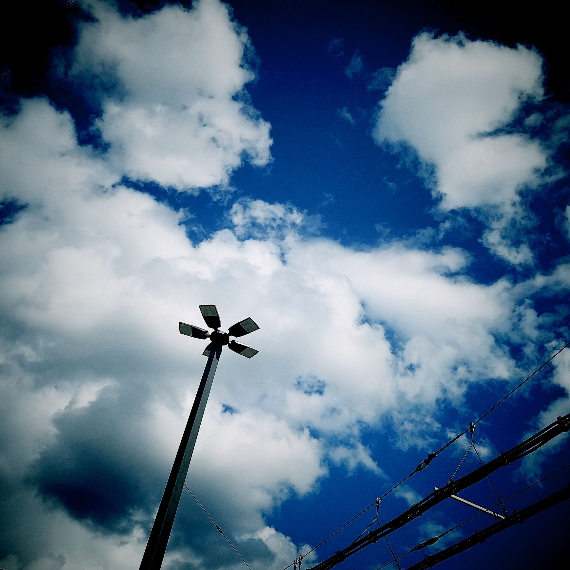 Zerrissene weiße Wolken hinter einer vielarmigen Straßenlaterne