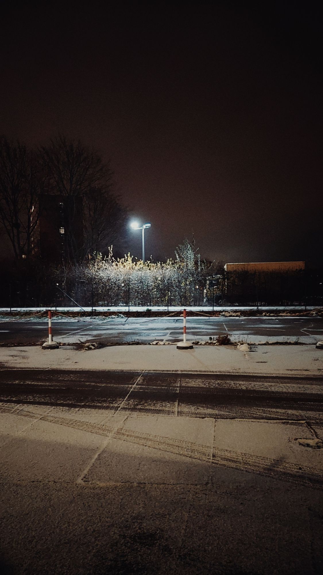 An empty parking lot, partially under snow.