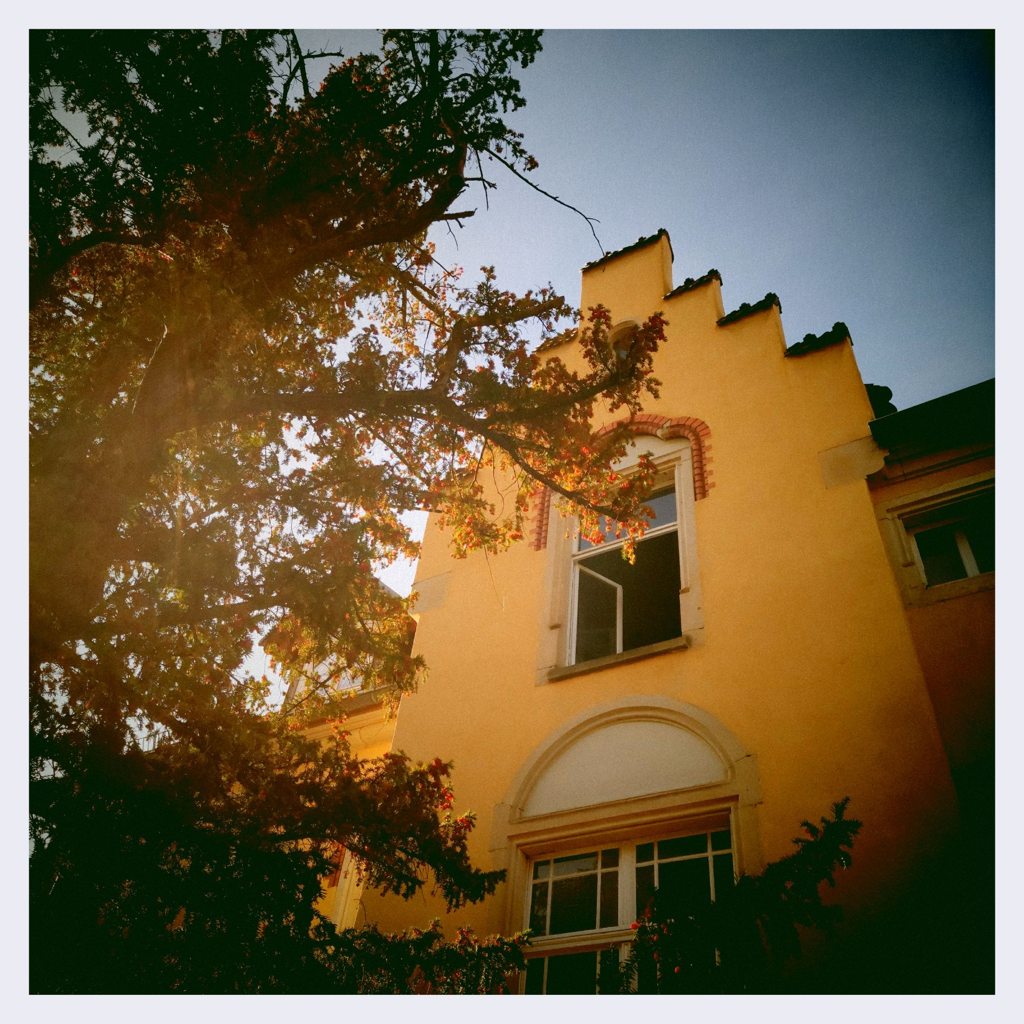 Facade of an old house, window opened, in front of blue sky.