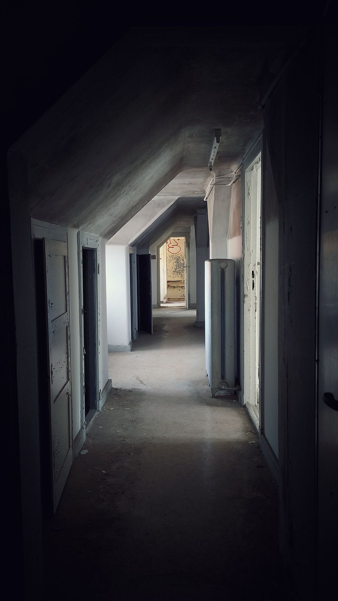 A longer corridor in an upper floor, just below the roof. Strong contrast. 