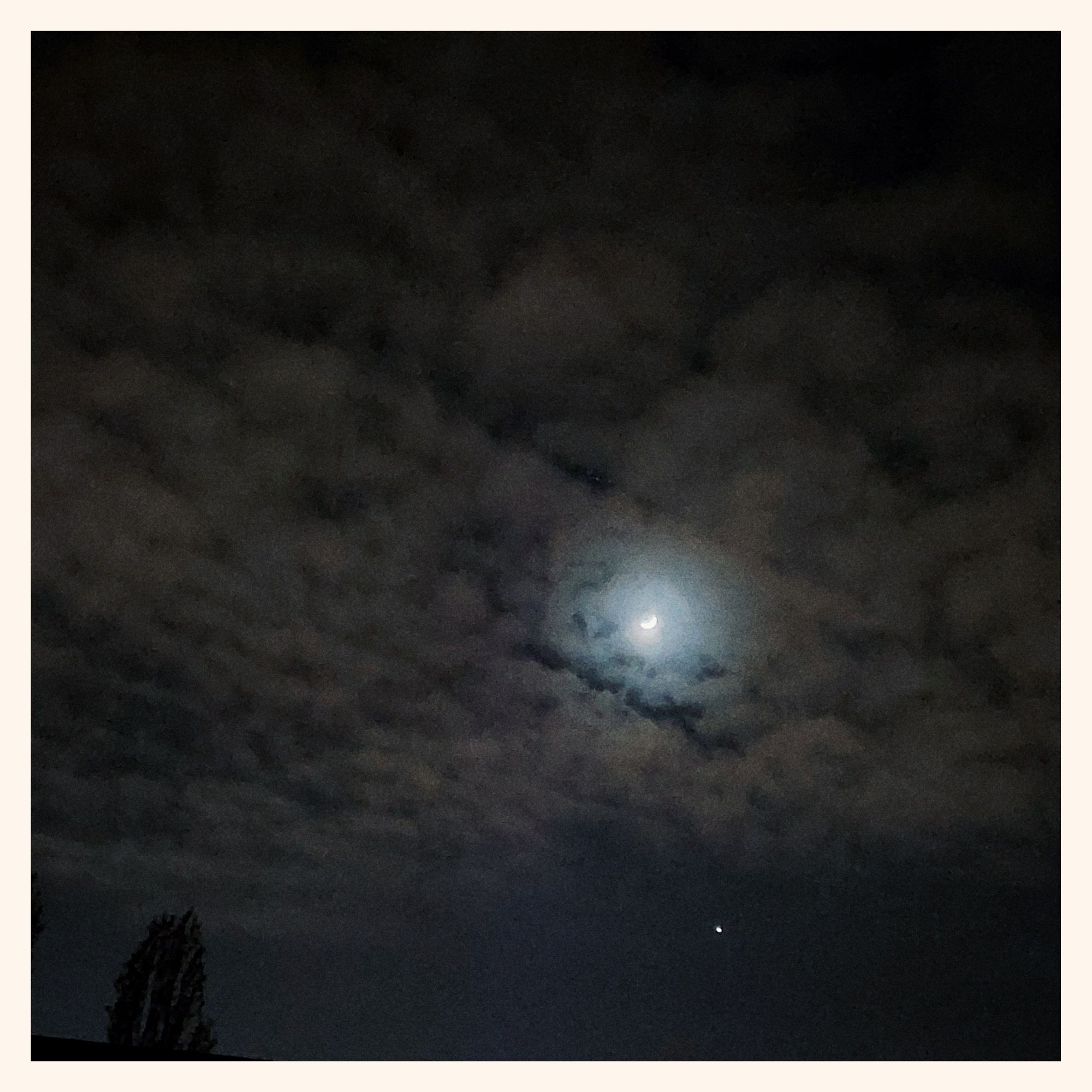 Moon and jupiter in a cloudy nightsky. Noisy, grainy shot with a bit of light in it.