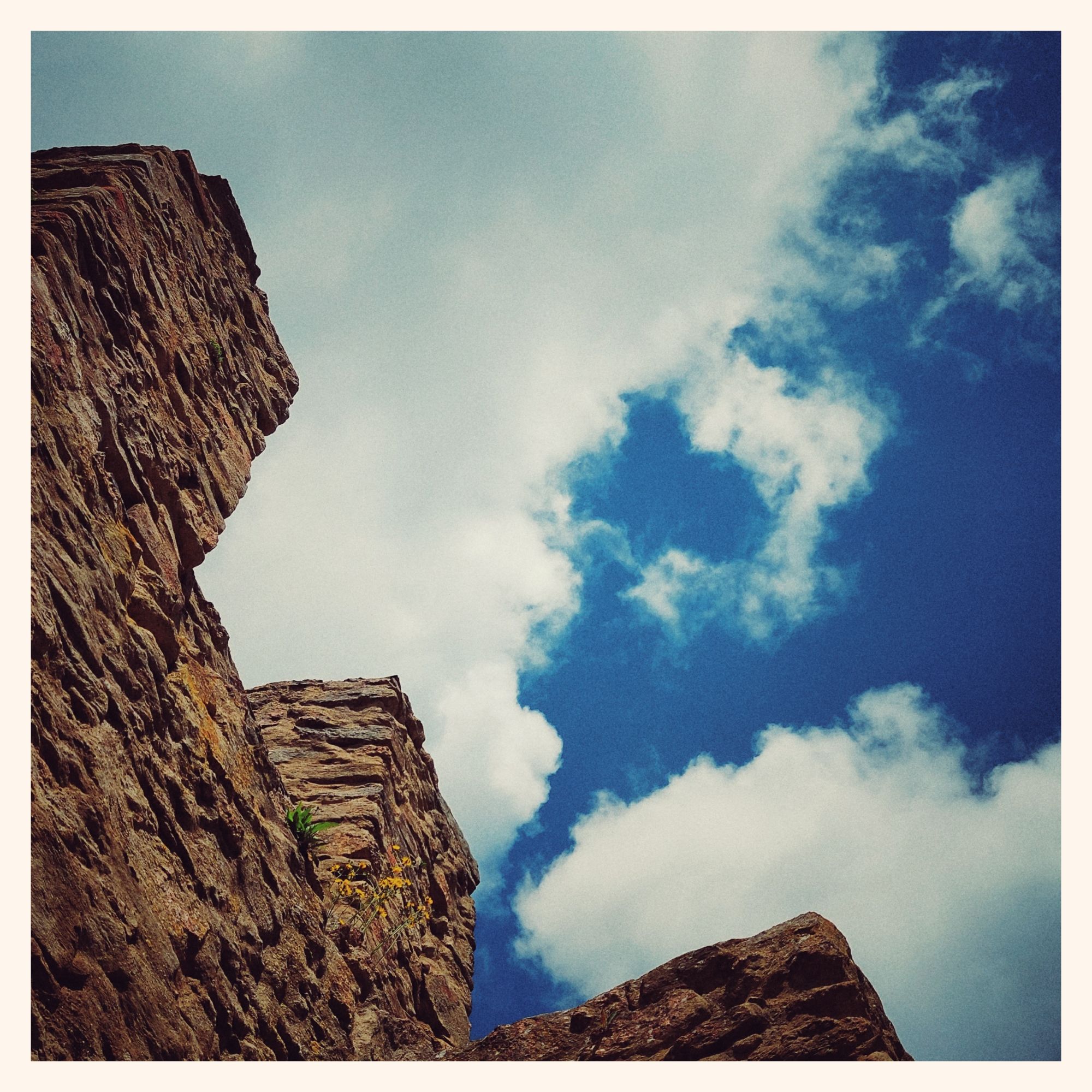 White clouds and a deep blue sky, above castle ruins. 
