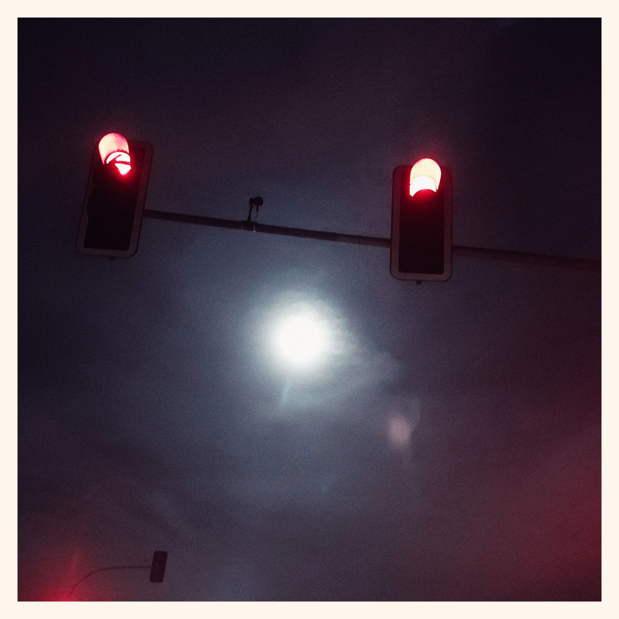 Moon in a hazy sky. Traffic lights in front.