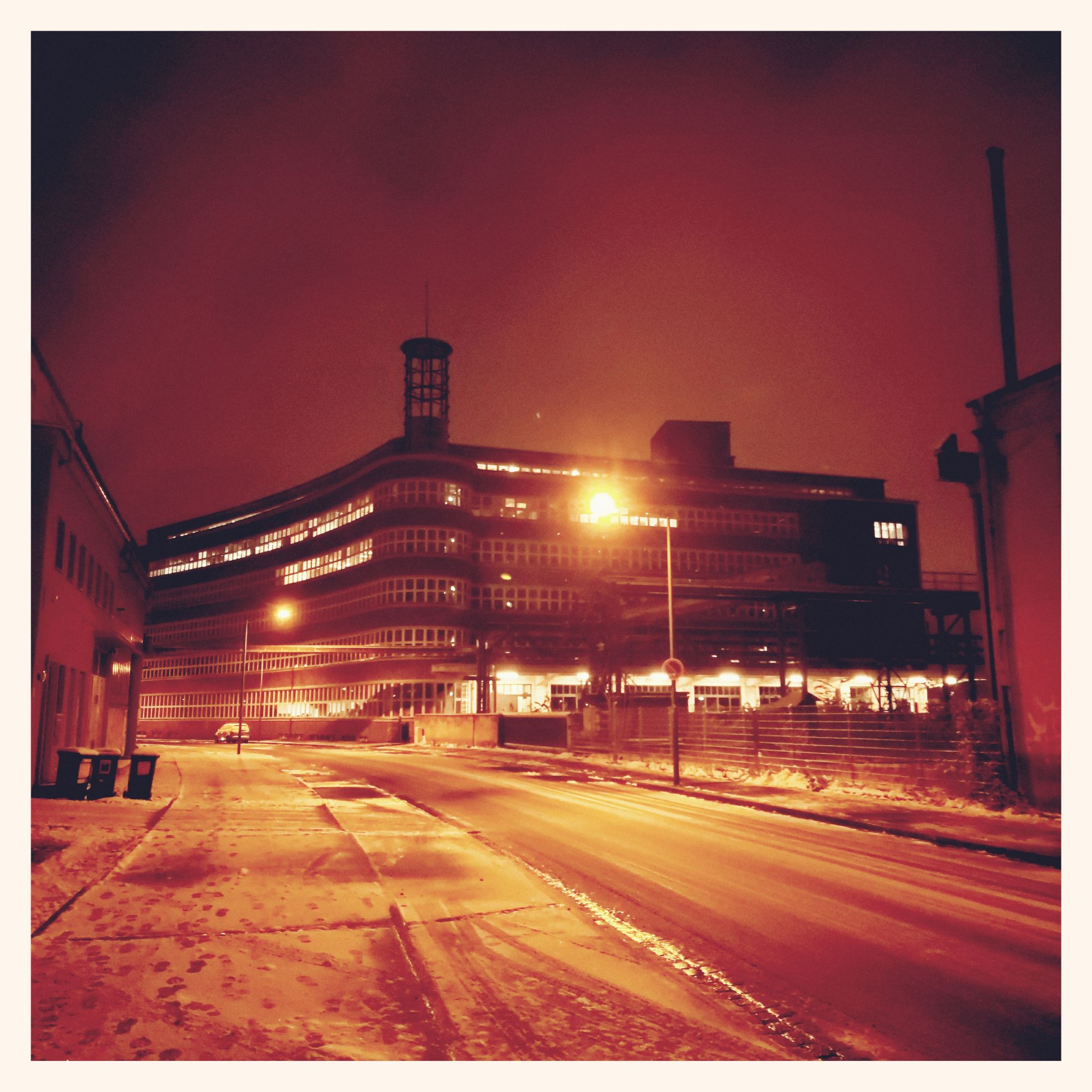 An old factory building near an empty street, late light.