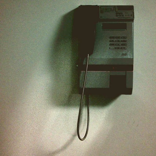 An old landline phone on a grey wall.