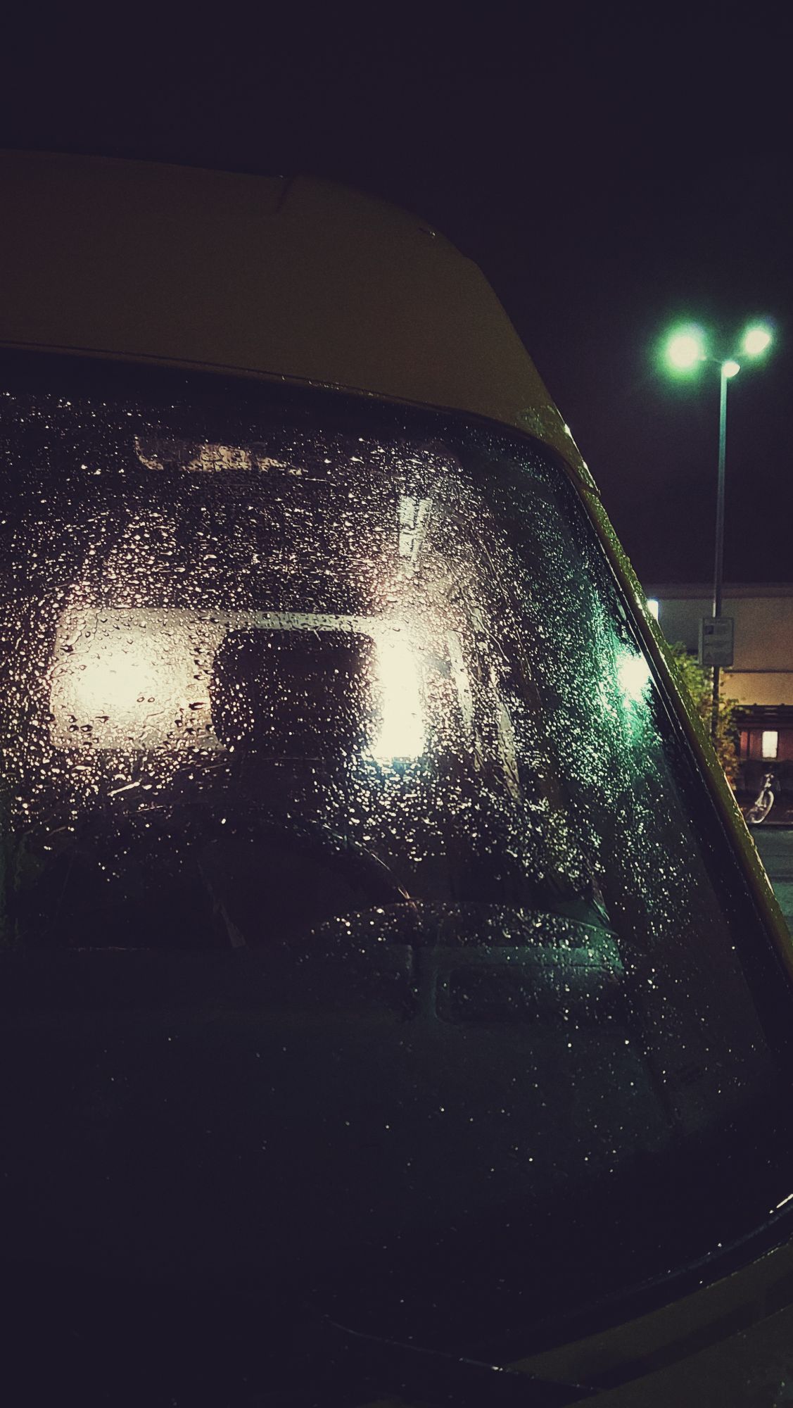 A windscreen of a car, with raindrops spilled over.