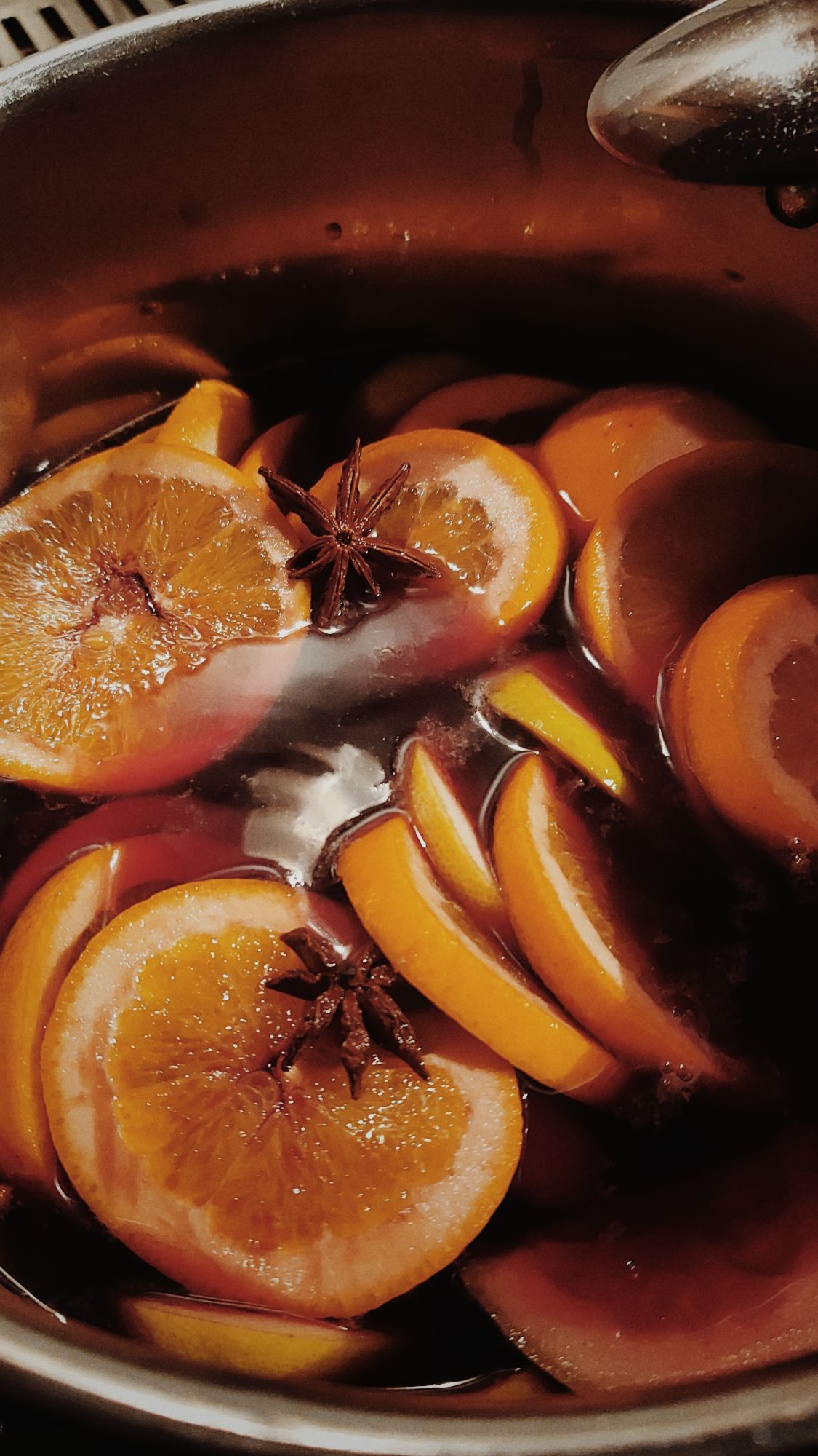 Slices of lemons and oranges in a pot of spiced red wine.