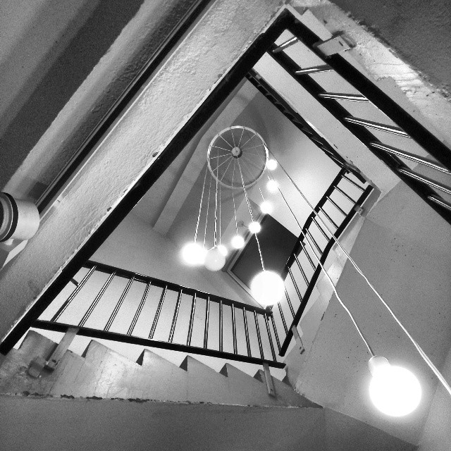 Lightbulbs hanging from a ceiling in the midst of a concrete staircase.