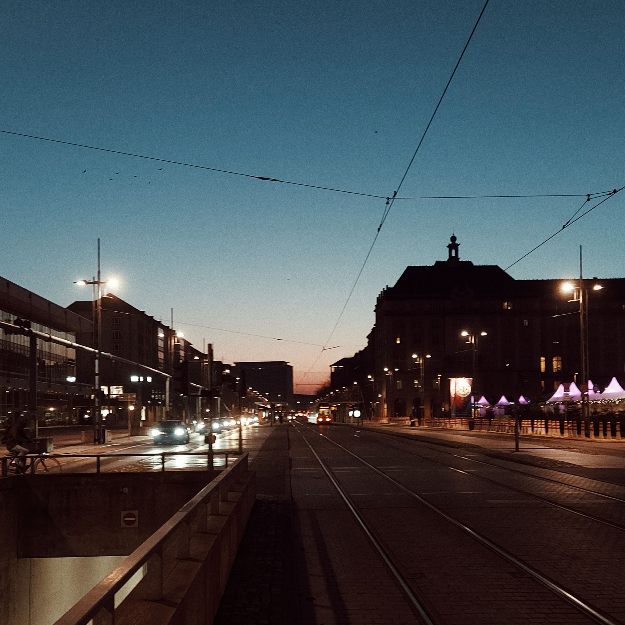 City dawn, tram tracks, waking traffic. 