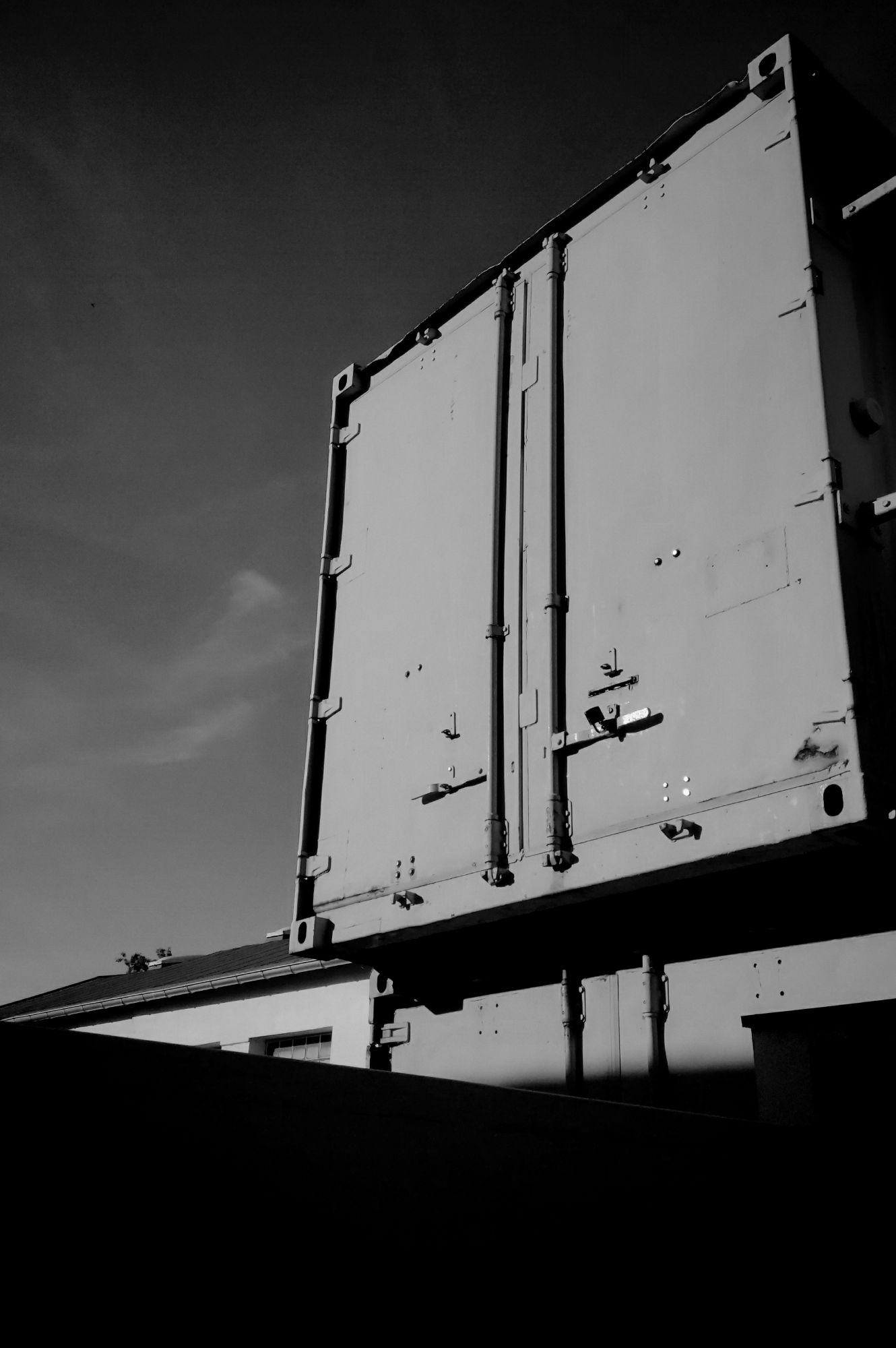 A container up on a wall, sky behind. Monochrome.
