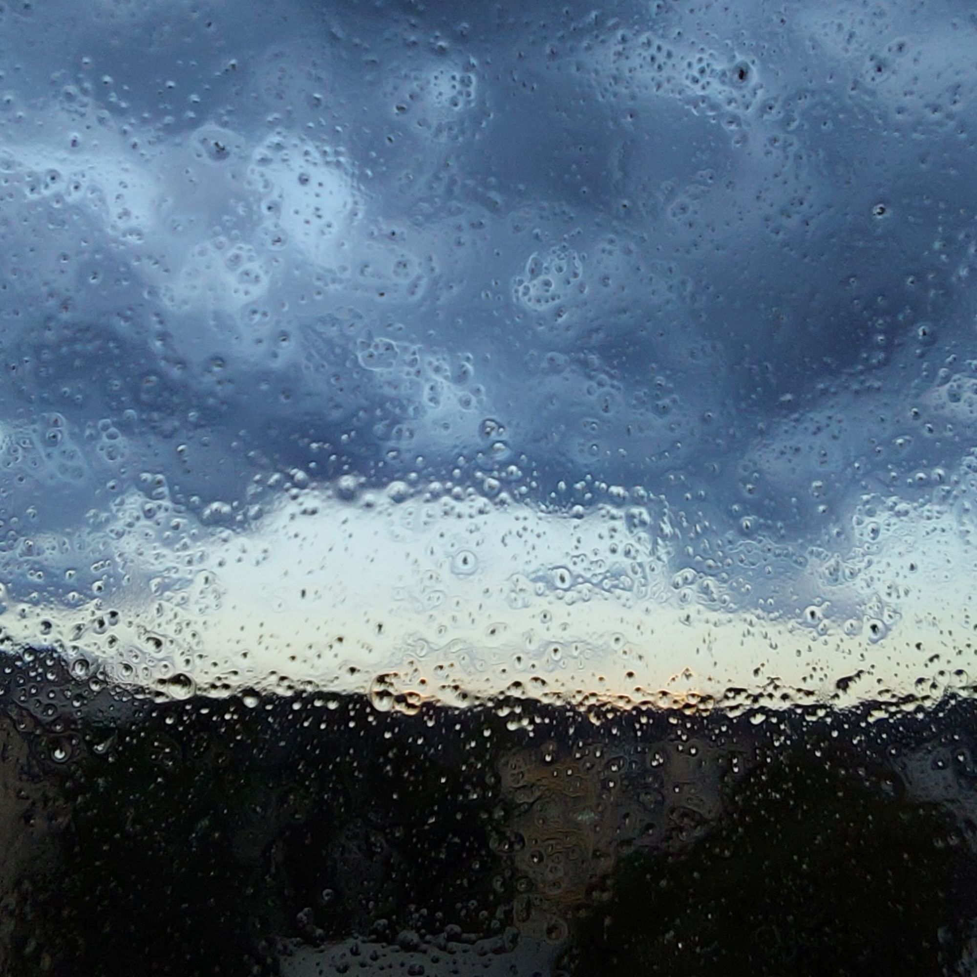 Dense clouds and sunset through a wet windowpane 